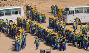 Foreign construction workers queue for buses back to their accommodation camp in Doha.