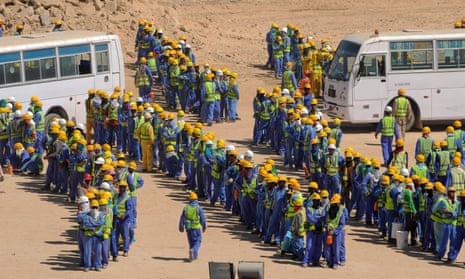 Construction workers queue for buses back to their accommodation camp in Doha, Qatar.