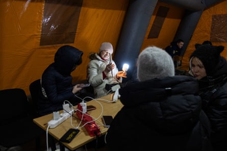 People on phones and holding lamps in a tent.