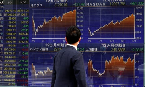 A man walks past a Nikkei stock index at a brokerage in Tokyo