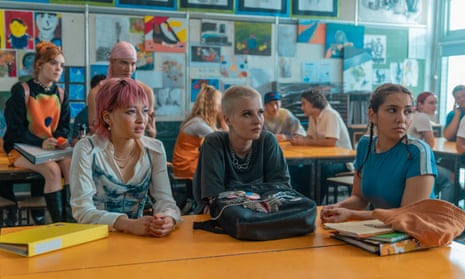 A scene of three characters from Heartbreak High sitting at desks in a classroom with their classmates at desks behind them