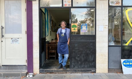 Sergio Helman de pie en la puerta de su restaurante mientras usa un delantal