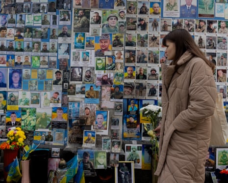 A woman holding flowers pays her respect at the Wall of Remembrance of the Fallen for Ukraine in Kyiv, Ukraine.