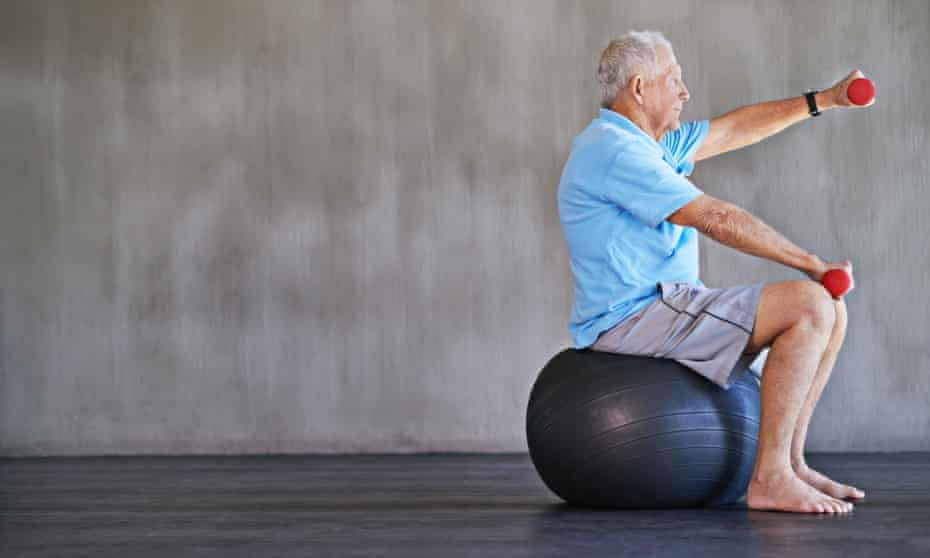 A man uses weights while sitting on an inflatable ball