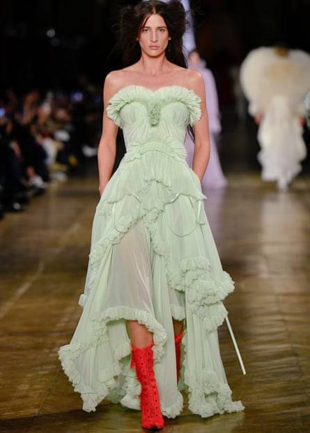 A model wearing a long, strapless lacy mint-green dress and red laced boots