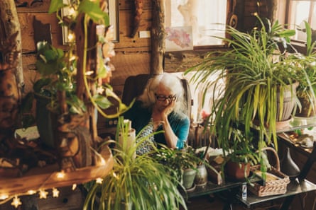 A woman watches television while surrounded by potted plants