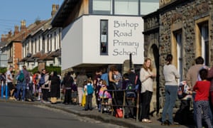 A queue of adults and children along a road