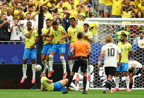 Brazil's Casemiro and teammates jump in a defensive wall after Japan's Ritsu Doan shoots at goal.