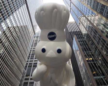 The huge Pillsbury Doughboy balloon among tall buildings