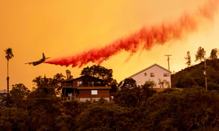 An airplane drops fire retardant over homes in the Spanish Flat area of Napa, California, as flames rage through on 18 August 2020.