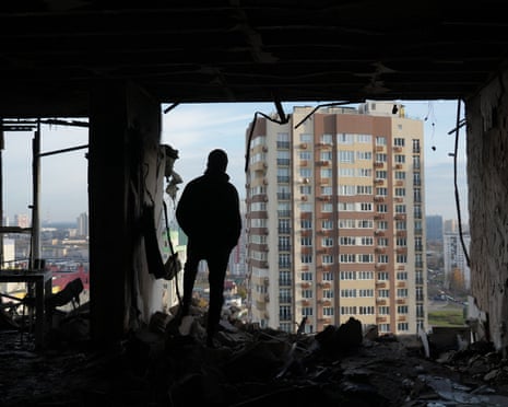A person stands in a destroyed apartment in a damaged residential building following an air strike on Kyiv.