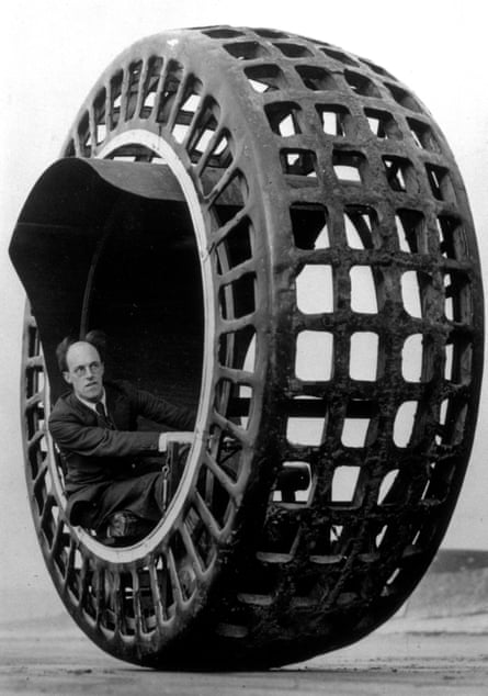 Black and white photograph of JA Purves sitting inside the Dynasphere, a large (perhaps 12ft diameter) wheel with a tyre that is in a mesh form, with large square holes in regular lines.