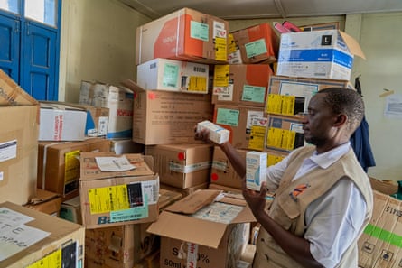 A man checks boxes stacked against the wall of a room.