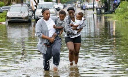 Jalana Furlough carries her son Drew Furlough as Terrian Jones carries Chance Furlough in New Orleans after flooding on Wednesday.