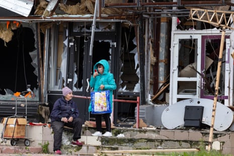 Women try to use their phones outside a destroyed building in Izium.