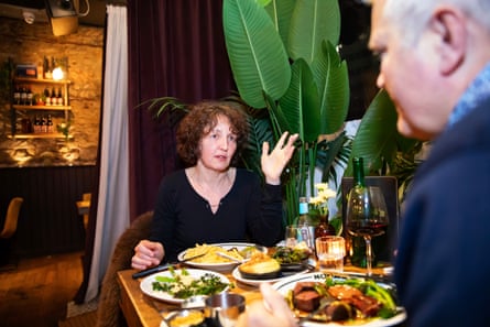 A woman and man facing each other across a restaurant table