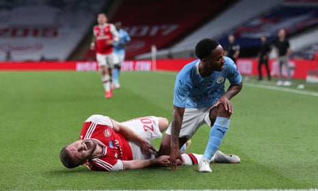 Shkodran Mustafi of Arsenal goes down injured as Raheem Sterling of Manchester City reacts.