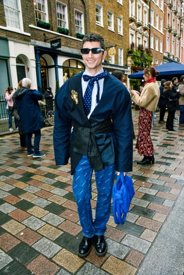 A person wearing a navy blazer and patterned jeans