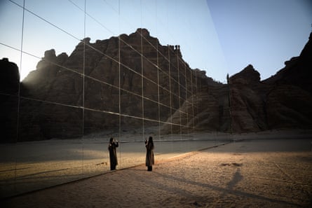 A woman takes selfies in front of the largest mirrored building in the world, the Maraya in Alula