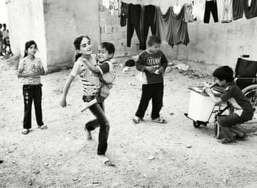 a girl runs smiling carrying a young booy while three children are playing around her
