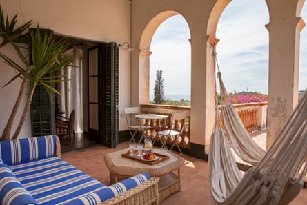 An outside terrace with a sofa, hammock, tables and chairs.