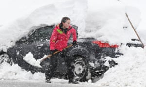 Woman removes snow from car in Germany