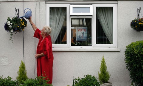 Barbara House who supports Brexit, waters her plants outside her house while a poster advertising Britain leaving the EU is attached to her window in Headington outside Oxford on June 23, 2016. 