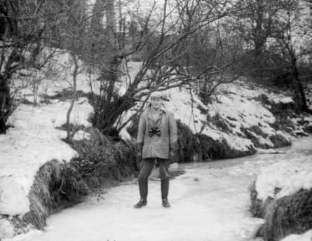 Black and white photograph from 1963 of a man standing on a frozen stream, binoculars around his neck