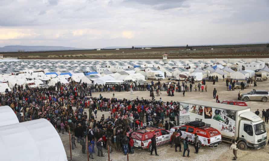 Syrians, who fled bombing in Aleppo, wait in a queue to get food at a tent city and close to the Bab al-Salam border crossing on Turkish-Syrian border