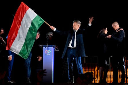 Péter Magyar waves a Hungarian flag on stage after the announcement of the partial results of the parliamentary election in Budapest