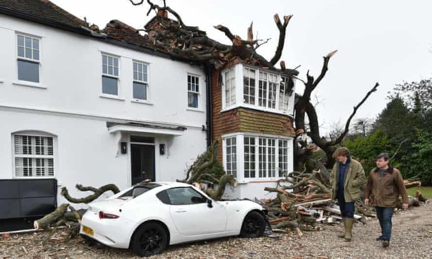 Sven Good, 23, and his father Dominic, walk past the damaged car and home in Stondon Massey, near Brentwood, Essex.