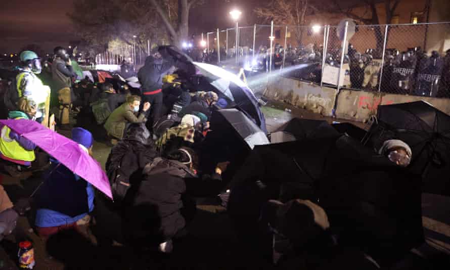 Demonstrators use umbrellas for protection as police fire pepper spray and rubber bullets during a protest outside of the Brooklyn Center police station on 14 April 2021 in Brooklyn Center, Minnesota. This was the fourth day of protests in the suburban Minneapolis city following the fatal shooting of 20-year-old Daunte Wright by Brooklyn Center police officer Kimberly Potter.