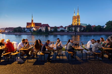 A view across the River Oder in Wrocław to an illuminated church.