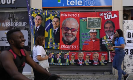 Towels featuring President Jair Bolsonaro, left, and former President Luiz Inacio da Silva, or Lula, hang for sale next to a chalkboard showing the vendor’s daily sales count for each presidential contender towel, in Rio de Janeiro last month