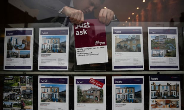 An estate agent changes for sale cards in the window