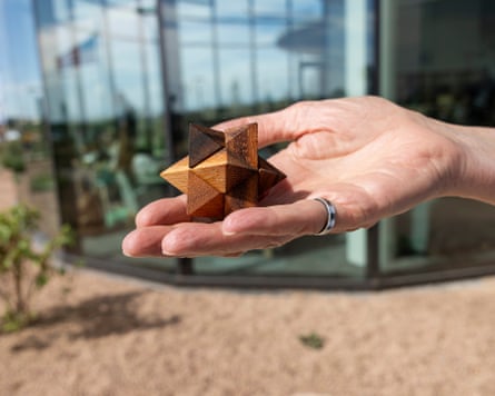 A hand holding a wooden star-shaped 3D puzzle.