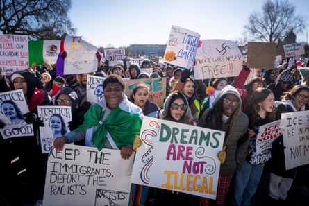 crowd of people hold up signs in protest