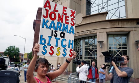 woman holding up sign reading 'alex jones karma is a bitch'