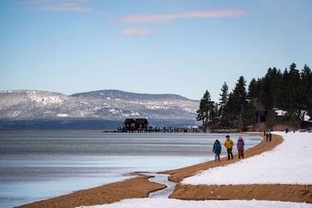Three group stepping connected a sandy agelong of a snow-covered beach, alongside a reservoir pinch evergreen trees and debased hills beyond.