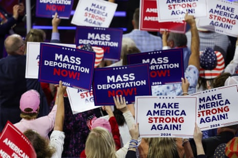 people hold signs that read 'mass deportation now' and 'make America strong again'