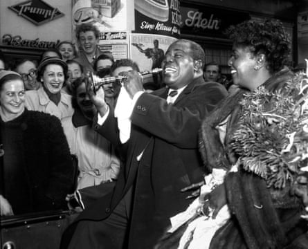 Jazz great Louis Armstrong plays a child’s trumpet in Dusseldorf, Germany, Oct. 13, 1952 file photo. His wife Lucille is at right.