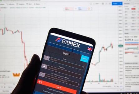 BitMEX cryptocurrency exchange logo and application on a phone, with a graph in the background