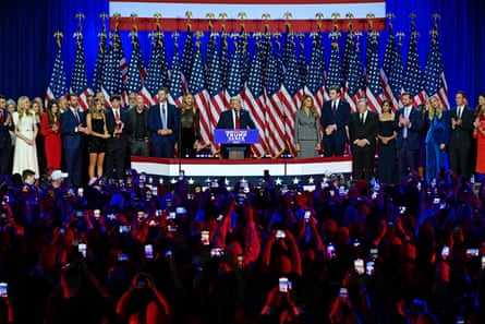 man speaks on stage in front of crowd of people