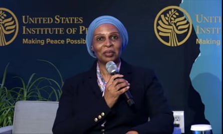 Dr Fatima Akilu holds a microphone, wearing a navy blazer and blue head scarf
