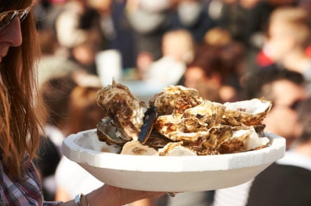 A woman in profile holds a large plate of oysters