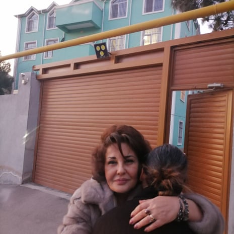 Two women hug outside a big building