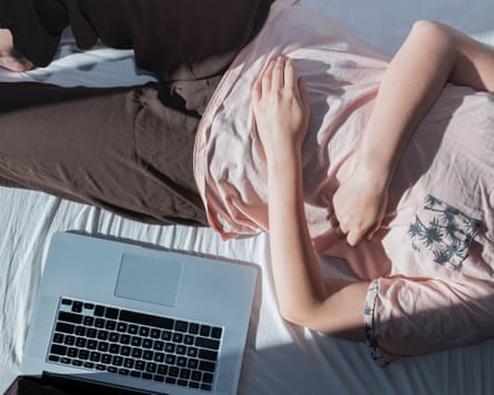 Woman rests in bed next to a computer