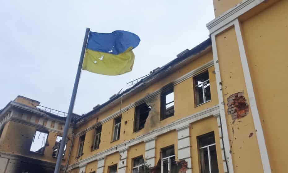 The Ukrainian national flag flying in front of a school hit by shelling in Kharkiv.