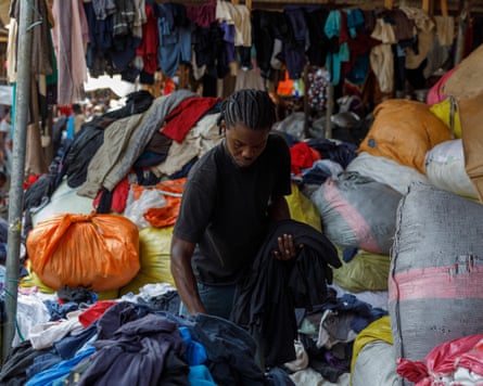 Um homem separa fardos de roupas de segunda mão