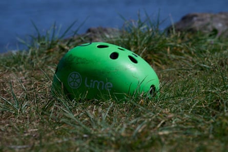 Sunlit bright green bicycle helmet, featuring Lime Bike logo, left on grass beside the Yarra River